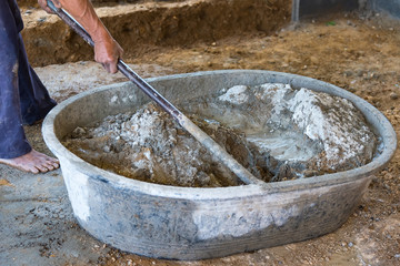 Worker Mixed Cements in Basin Mixer with Hoe in construction site.
