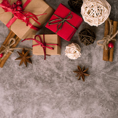 Christmas dark aged cement background with red decorations wrapped in a wrapper with ribbons, gifts, snowflakes, striped candy, and rattan balls of white and brown colors