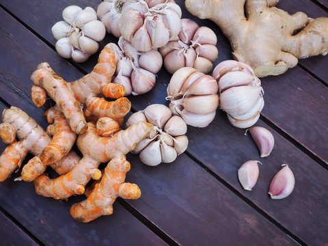 Top view of set of herbs, food condiments with turmeric, ginger and garlic on dark wooden table background.