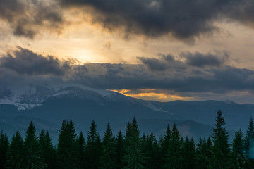 Evening dramatic sky with colorful burning clouds against the backdrop of mountain houses in winter