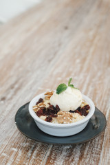 Apple crumble dessert with vanilla ice cream on the top on wooden table