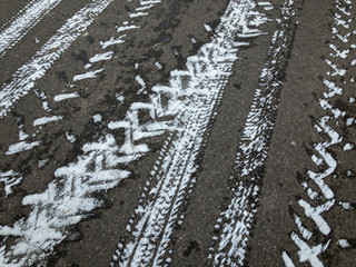 Fototapeta premium snowy asphalt road covered with tyre tracks in winter day
