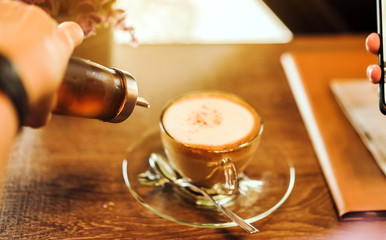 A woman poured the syrup into the saucer of the coffee cup while absent-mindedly playing the...