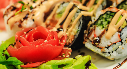Red carved tomato on background of sushi in sous. Restaurant delicious dish decorated in fancy style. Beautiful food decoration. Vegetable flower. 