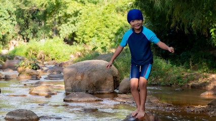 A kid wearing swimming suit in the river