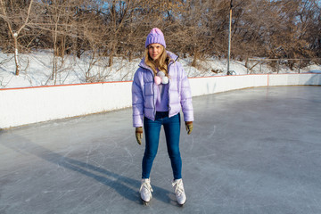 Lovely young woman riding ice skates on the ice rink.