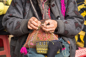 Red dzao ethnic minority woman sewing in Sa Pa, Lao Cai province, Vietnam. an elderly woman sews on...