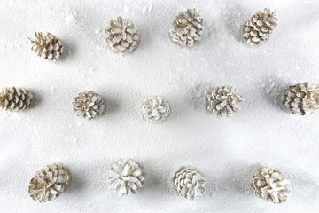 Fototapeta na wymiar Christmas decoration cones covered snow made of icing sugar top view. Christmas forest concept background. Golden colored pine cones covered sugar powder..