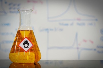 Erlenmeyer flask with Orange liquid and chemical hazard warning symbols labels (oxidizing agent...