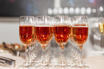 Rows of glasses with pink champagne on a festive buffet table. Exit registration of events. Close-up.