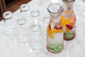 Infused detox water . Fruit infused flavored water, orange slice, piece of apple and kiwi slice in glass jar with glass.