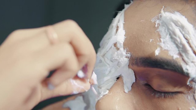 Make up artist applying white prosthetic insert on man's face to make a Halloween mask