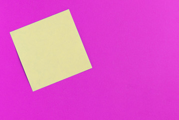 Fototapeta na wymiar Square yellow sticker note on a bright pink background close up