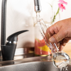 A man pours tap water into a glass flask.