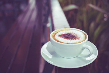 Coffee in white cup on weeden fence in the garden. vintage style effect picture.