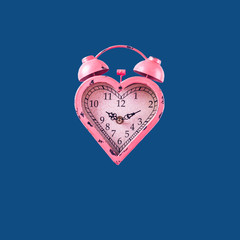 Heart shaped pink clock on classic blue background. Valentines day and love infitity and duration...
