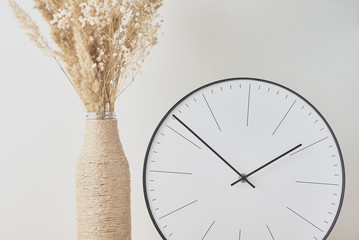 Classic round clock and homemade vase with a dries plant closeup