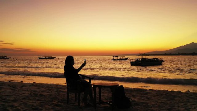 Seychelles, silhouette of the female tourist admiring the sunset on the tropical sandy beach