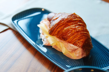 ham and cheese croissant, hot, lies on a blue plate, pastries