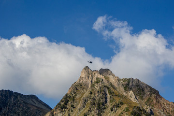helicopter flying over the top of a rocky mountain peak