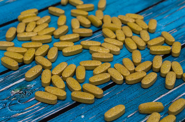 yellow sports multivitamins in tablets for men on a blue wooden background