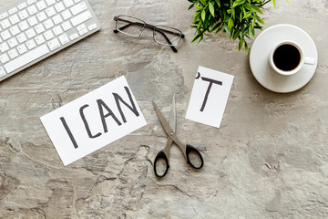 Motivation to be confident. Cut text I can't near scissors on grey office desk