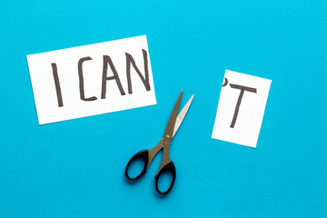 Motivation to be confident. Cut text I can't near scissors on blue desk