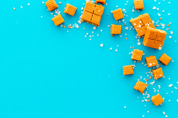 Salted caramel pieces - paradoxical sweets - on blue background top view frame copy space