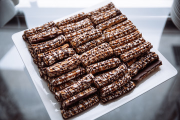 A chocolate-covered cookie sits on a white plate.