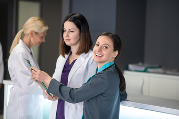 Three female doctors talking near reception in neurologycal clinic