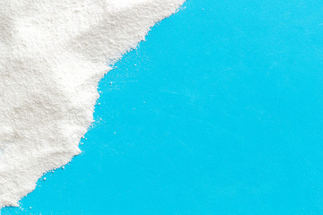 Washing powder scattered on blue background top view frame copy space