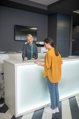 Blond receptionist in clinic offering time to a patient