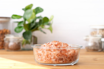 Fototapeta na wymiar A beautiful pinkish Himalayan salt in a glass bowl on the wooden kitchen table. The salt is mined in Pakistan and has very rich mineral, primarily used as a food additive as table salt. Cooking, Spa.
