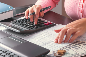 Business woman looking for the necessary data in a table in a document and calculates it on a...
