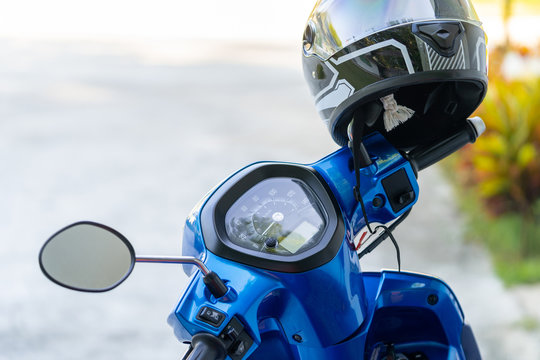 Close-up dashboard of a scooter in blue. Steering wheel and helmet on the mirror. Motorcycle driving concept. - Powered by Adobe