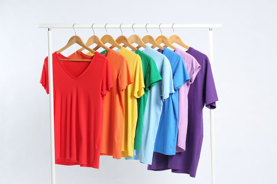 Colorful clothes hanging on rack against white background