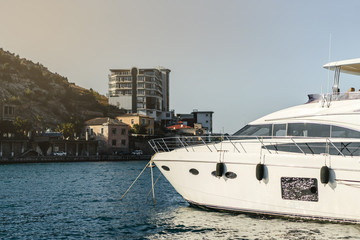 Fototapeta premium White luxury yacht anchored against the background of the coast. The bow of the boat, Balaklava, Crimea.