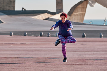 Fototapeta premium A woman doing stretching exercises outdoors - fitness and lifestyle concept