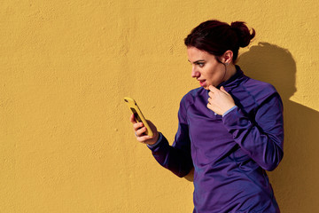 a young woman using her mobile phone while doing fitness outdoors - lifestyle concept