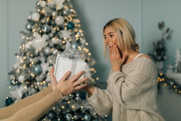 Happy couple giving presents for Christmas at home. Lovely christmas couple holding presents.