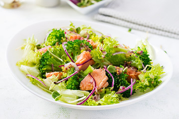 Salad of baked fish salmon, broccoli, lettuce, red onion and dressing. Fish menu. Seafood - salmon.