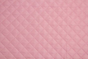 Quilted fabric. The texture of the blanket. Pink textile