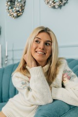 Beautiful woman in warm clothing on christmas tree background. Very beautiful girl with brown eyes at silver Christmas tree and smiling, close up