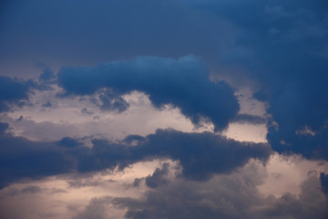 In the summer evening sky among other there are real dark blue clouds.