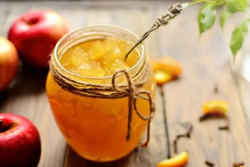Homemade apple jam with orange zest. Jam in a glass jar. Jam on a wooden background, top view. Place for text