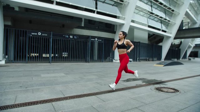 Fitness woman running near stadium in slow motion. Focused athlete girl jogging