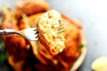Baked whole chicken curry. Festive dish on a dark background. Baked chicken sliced ​​with a fork.
