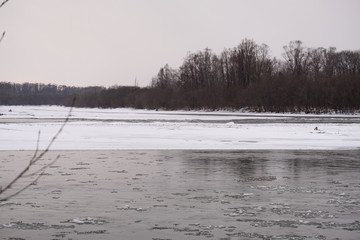 Mountain Russian river in winter. Snow on the shore. Rapid flow of ice water.