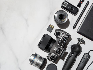 Photographer workplace with dslr camera, lens, pen tablet and camera accessorieson white marble...