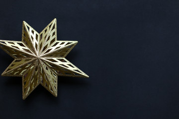 Flat lay: gold sparkling Christmas toy star on a dark blue background for New Year tree decoration.
